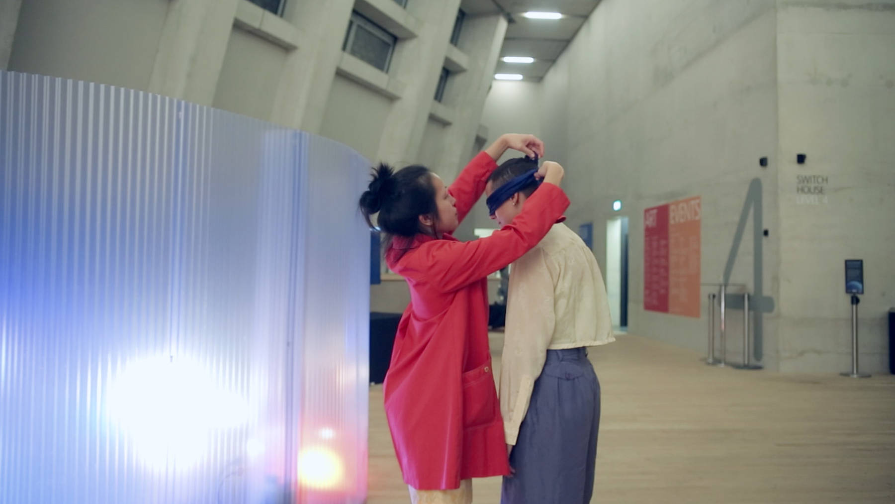 Jan Lee as the guide putting a blindfold onto the participant before leading them on a walk exploring sounds, space, stories and their body. Part of the immersive experience of Movement Alphabet by Jan Lee & Tim Murray-Browne, taken while exhibited at Tate Modern.